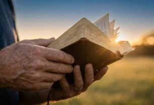 Maos segurando uma Biblia aberta ao ar livre durante o por do sol, luz dourada simbolizando a presenca do Espirito Santo