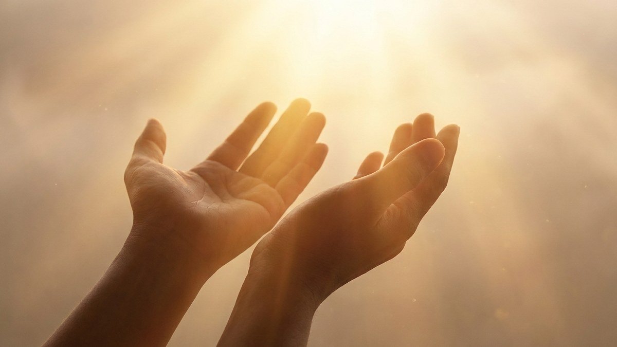 Mãos levantadas em direção à luz dourada vinda do alto, representando a cura interior e rendição espiritual a Deus